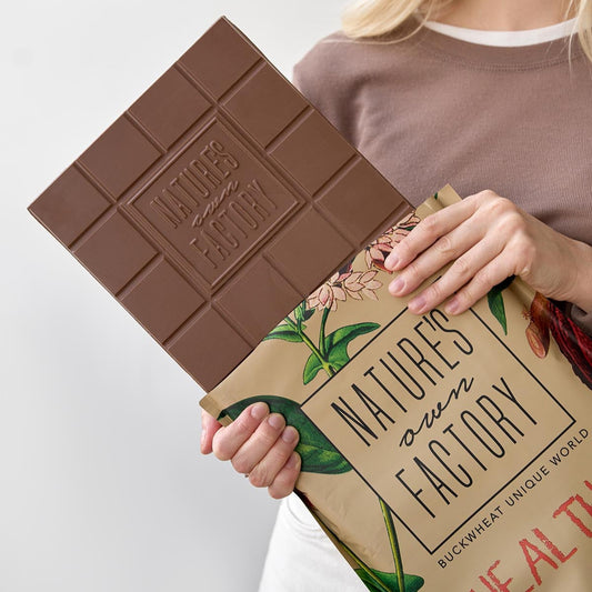 Person holding the milk chocolate bar 2kg and its packaging with the 'Nature's Own Factory' branding.