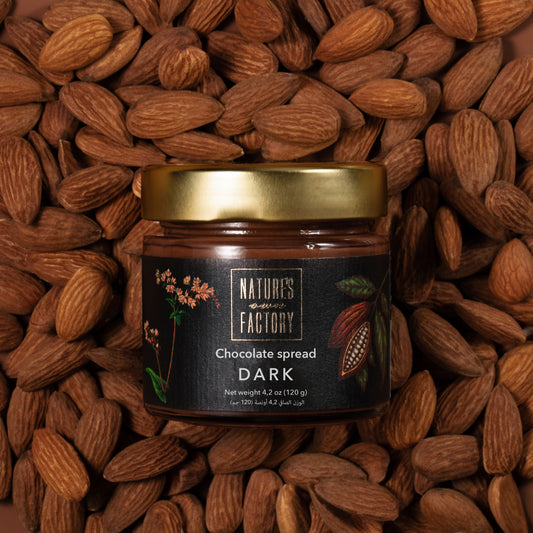 Nature’s Own Factory Dark Chocolate Spread jar placed on a bed of almonds nuts. Natural, handcrafted chocolate spread made in the UAE.