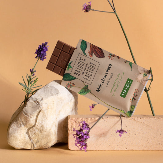 Nature's Own Factory Milk Chocolate bar and packaging with flowers and rocks on a beige background