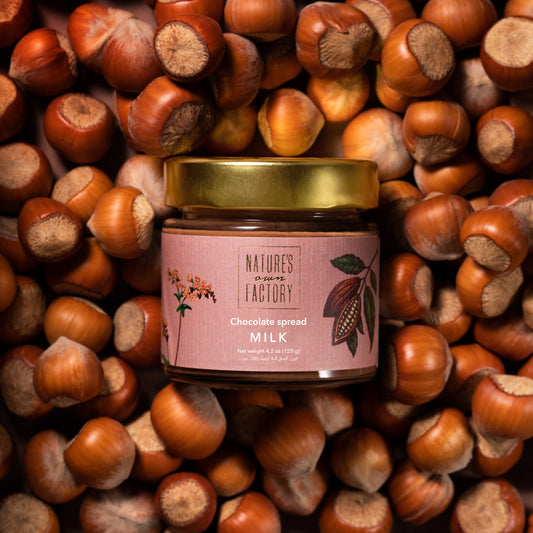 Nature’s Own Factory Chocolate Spread with hazelnut jar placed on a bed of hazelnuts. Natural, handcrafted chocolate spread made in the UAE.