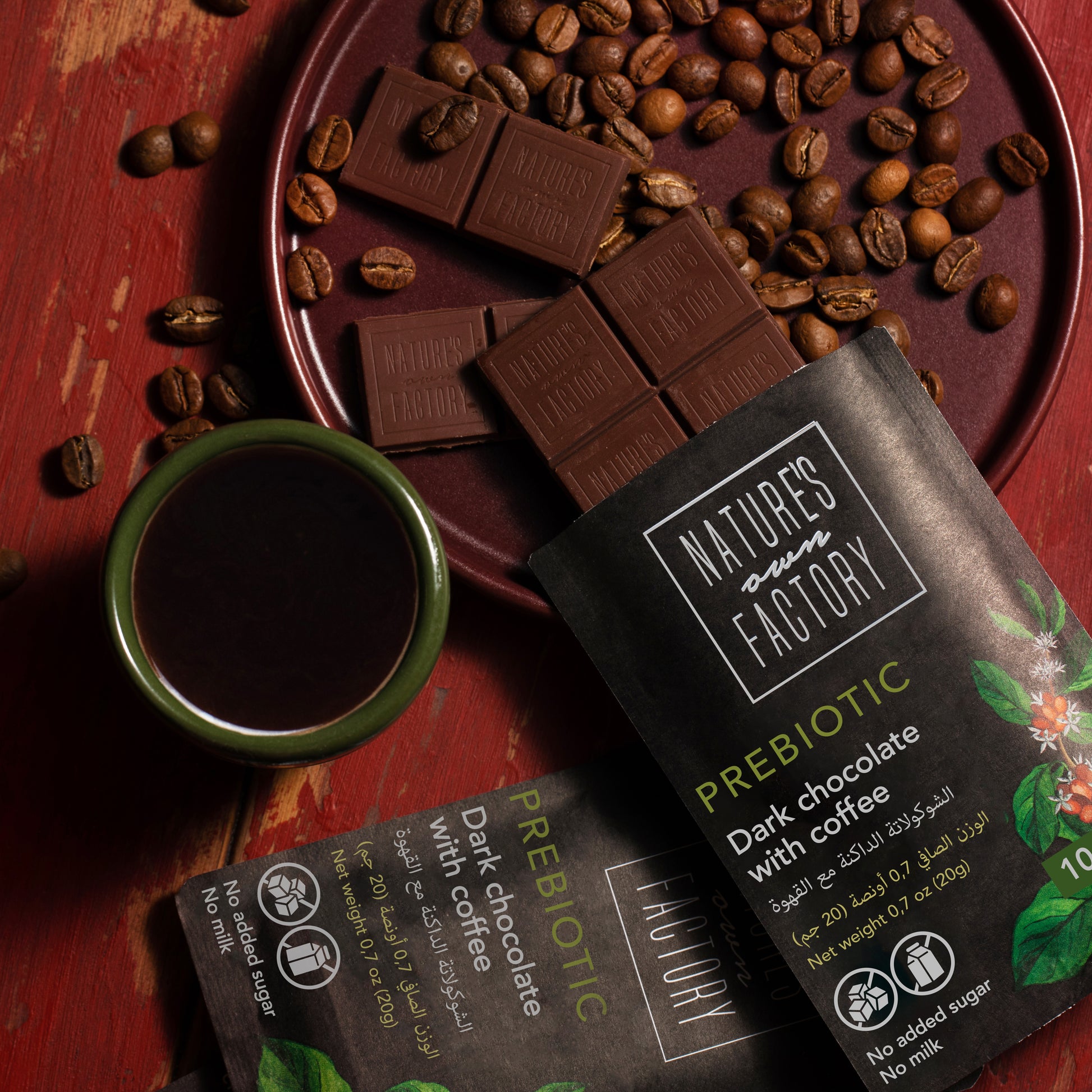 Nature's Own Factory prebiotic dark chocolate with coffee on a wooden surface with coffee beans and a cup of coffee.